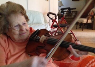 Elderly woman playing the violin with joy and concentration.