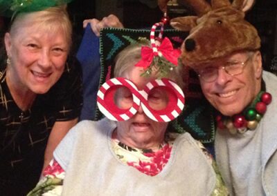 Three elderly people wearing fun holiday accessories and smiling.